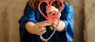 Femme tenant en stéthoscope en forme de coeur